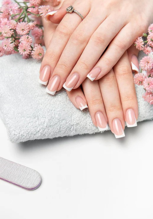 Classic French manicure surrounded by soft pink flowers